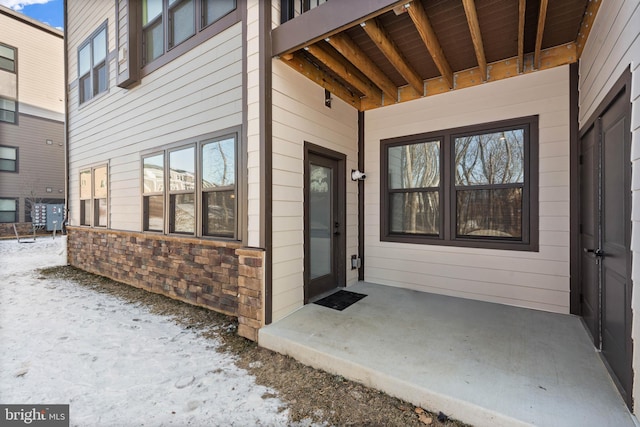 snow covered property entrance featuring a patio