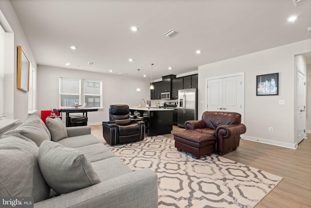 living room featuring sink and light hardwood / wood-style floors