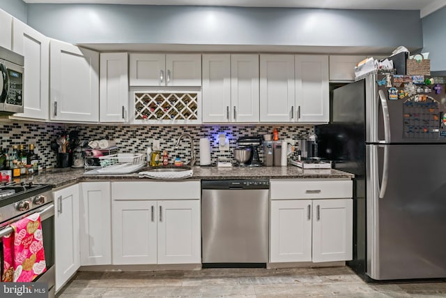 kitchen featuring dark stone counters, sink, stainless steel appliances, and white cabinetry