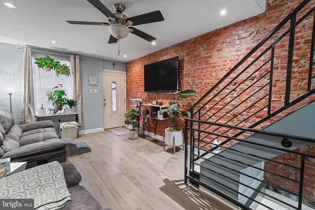 living room with ceiling fan, brick wall, and hardwood / wood-style flooring