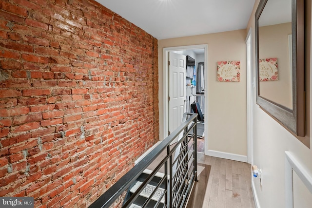 hall featuring brick wall and light wood-type flooring