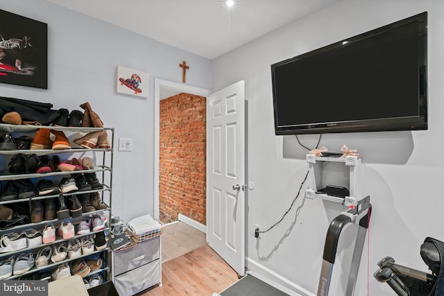 office space featuring brick wall and light hardwood / wood-style floors