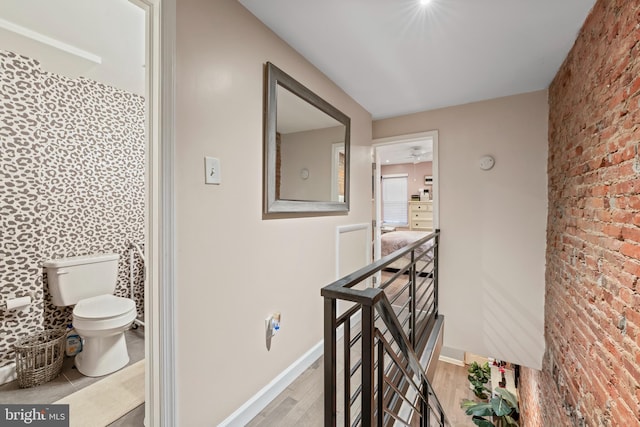 hallway featuring brick wall and light hardwood / wood-style flooring