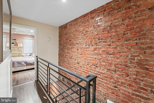 hallway with dark wood-type flooring and brick wall