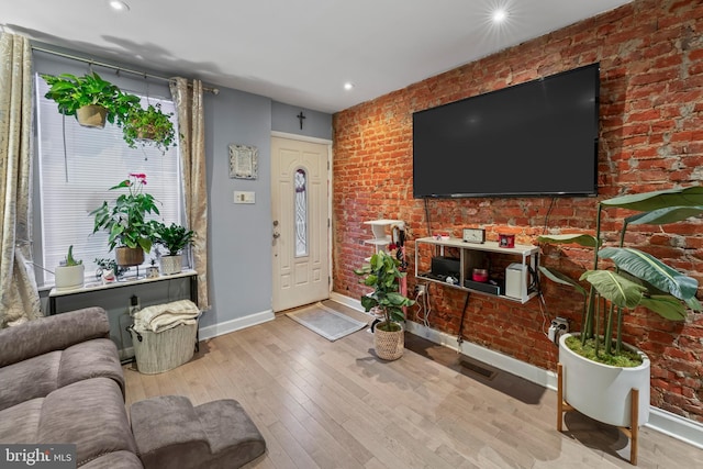 living room with brick wall and light hardwood / wood-style flooring