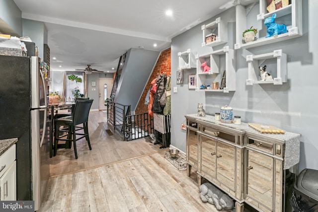 kitchen featuring ceiling fan, stainless steel fridge, light stone counters, and light hardwood / wood-style floors