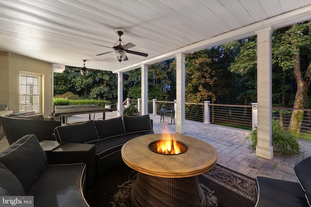 view of patio / terrace with ceiling fan and an outdoor living space with a fire pit