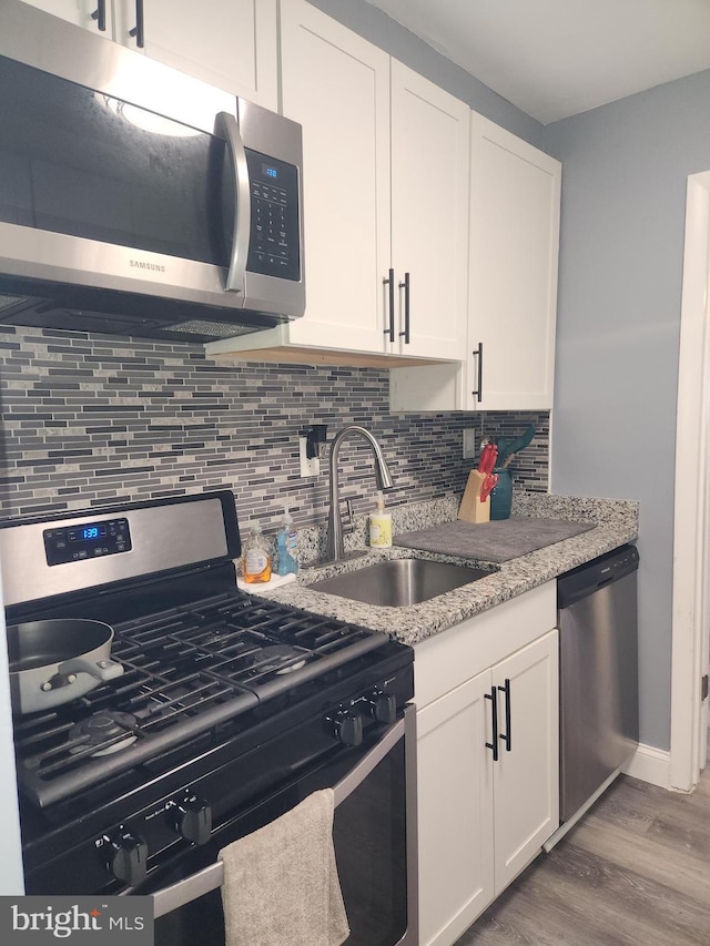 kitchen featuring sink, stainless steel appliances, white cabinetry, and decorative backsplash