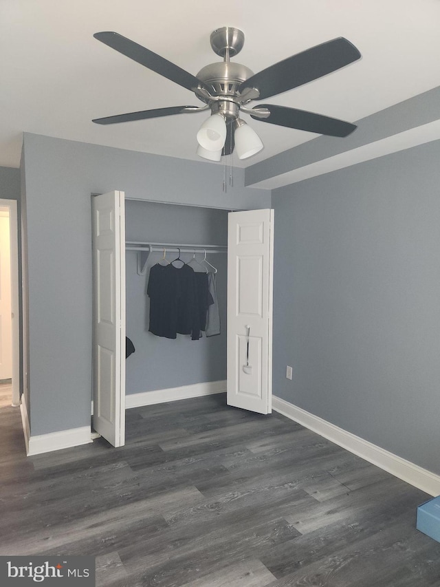 unfurnished bedroom with dark hardwood / wood-style floors, a closet, and ceiling fan