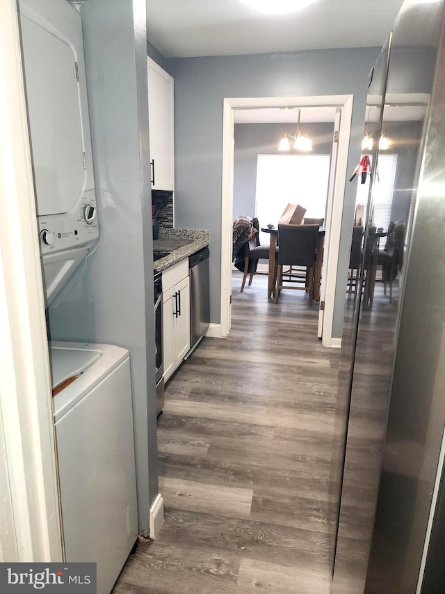 kitchen featuring dark hardwood / wood-style flooring, white cabinets, stacked washer and clothes dryer, an inviting chandelier, and stainless steel appliances