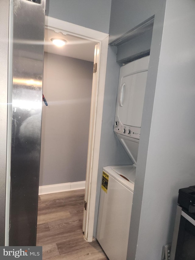 clothes washing area featuring hardwood / wood-style flooring and stacked washer / dryer