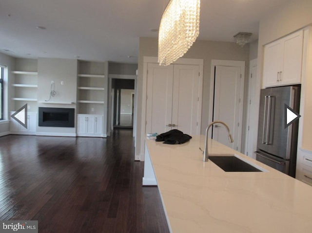 kitchen with hanging light fixtures, high end refrigerator, dark wood-type flooring, white cabinets, and sink