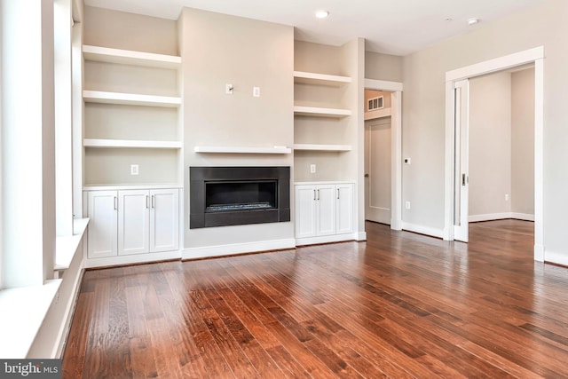 2 Stationmaster St SE Unit 302, Leesburg, VA 20175 - unfurnished living room featuring a glass covered fireplace, dark wood-style floors, built in shelves, and visible vents