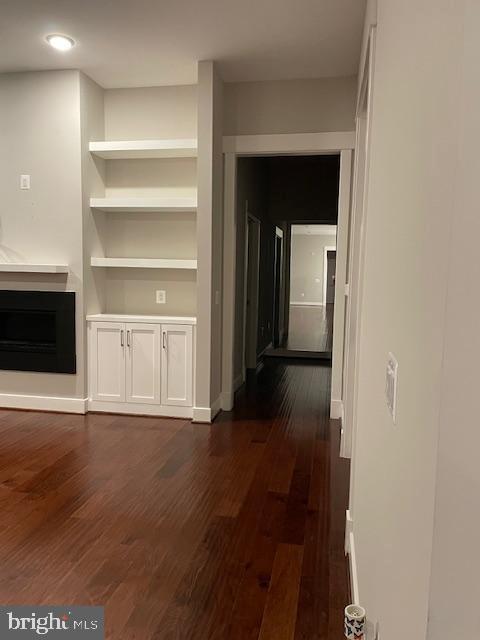 unfurnished living room with dark hardwood / wood-style flooring and built in shelves