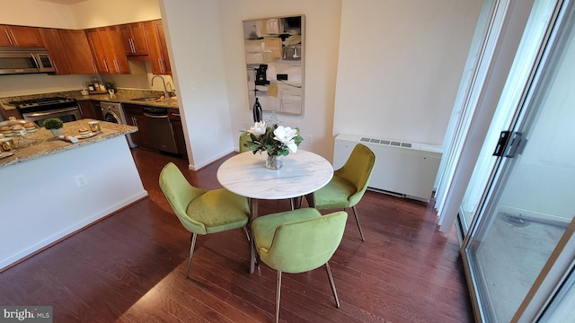 dining room featuring dark wood-type flooring, sink, and radiator heating unit