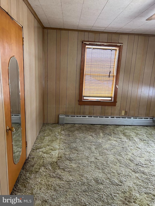 carpeted spare room with wooden walls and baseboard heating