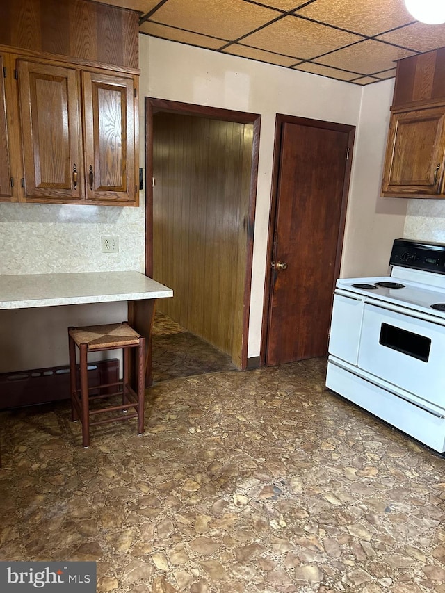 kitchen featuring a paneled ceiling, a kitchen bar, and electric range