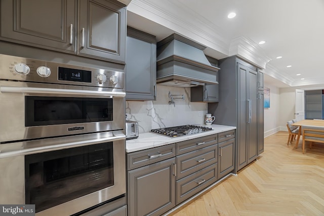 kitchen with premium range hood, appliances with stainless steel finishes, ornamental molding, light parquet flooring, and backsplash