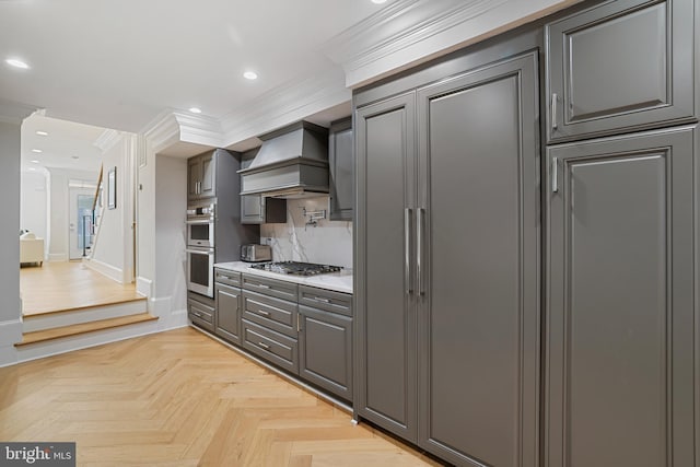 kitchen with light parquet floors, stainless steel appliances, ornamental molding, custom range hood, and decorative backsplash