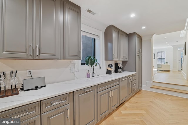 kitchen featuring light stone counters, sink, and light parquet flooring