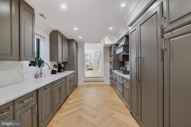 kitchen with sink, crown molding, light parquet floors, premium range hood, and light stone counters