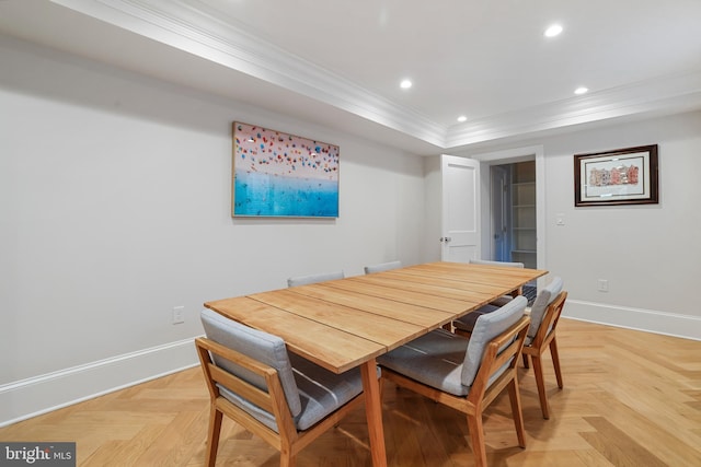 dining space with a tray ceiling, crown molding, and light parquet flooring