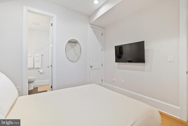 bedroom featuring ensuite bathroom and wood-type flooring