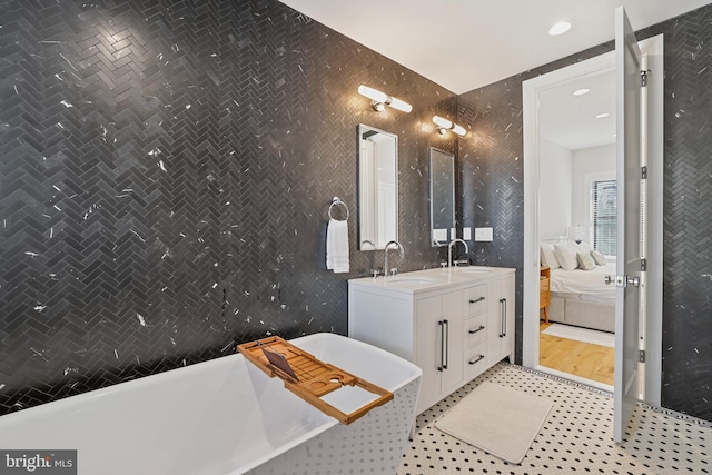 bathroom with tile walls, a washtub, tile patterned flooring, and vanity