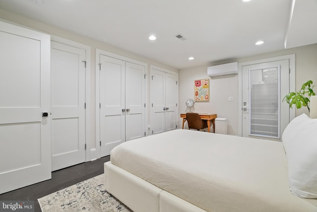 bedroom featuring a wall mounted air conditioner, two closets, and access to outside