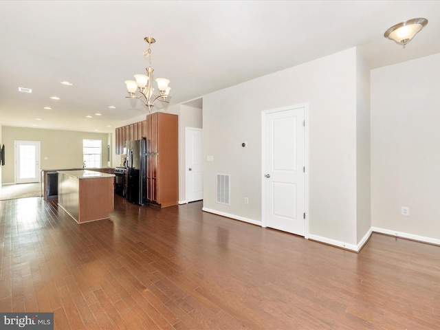 kitchen with dark hardwood / wood-style flooring, decorative light fixtures, a center island, an inviting chandelier, and black fridge