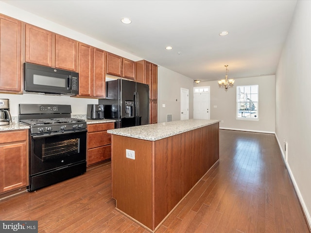 kitchen with black appliances, a kitchen island, decorative light fixtures, dark hardwood / wood-style floors, and a notable chandelier