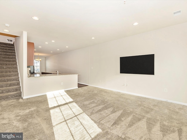 unfurnished living room featuring light colored carpet, sink, and a chandelier