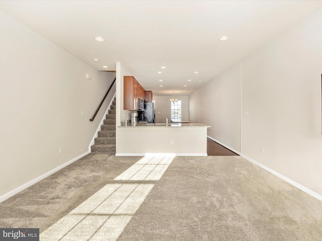 unfurnished living room with carpet floors, sink, and a chandelier