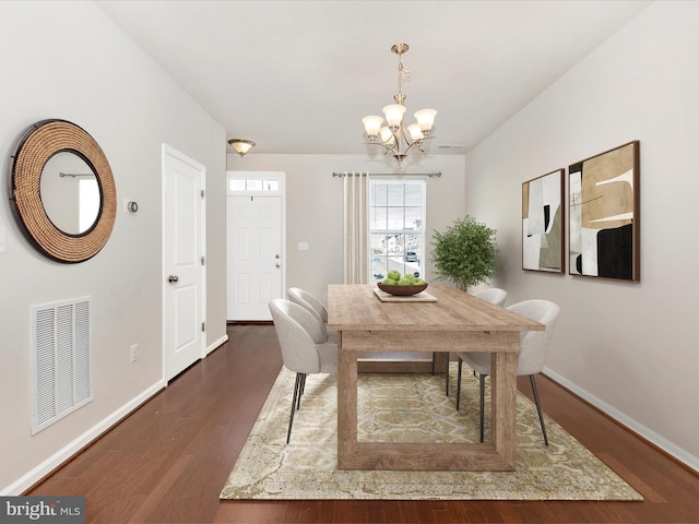 dining space with dark hardwood / wood-style floors and an inviting chandelier