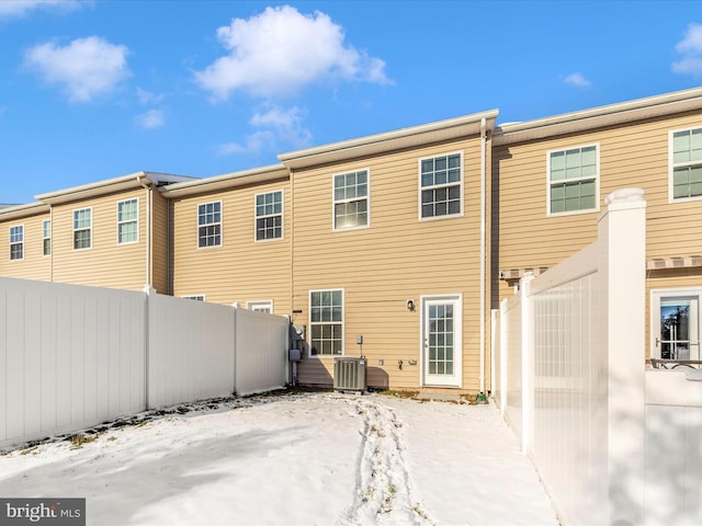 snow covered rear of property featuring central AC