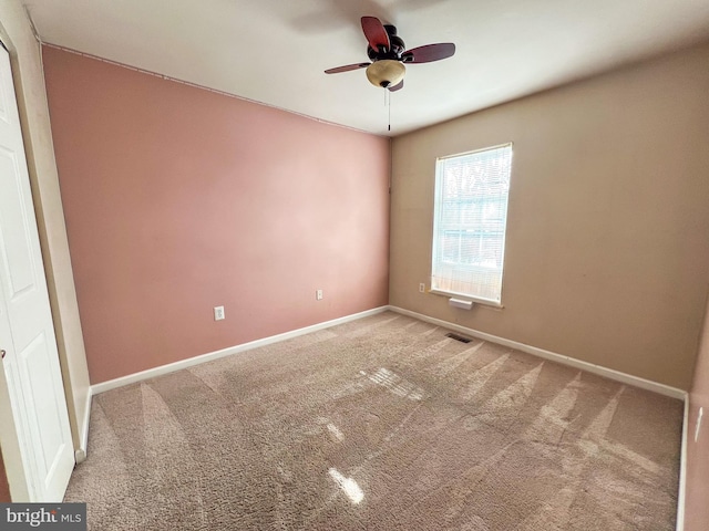 empty room featuring ceiling fan and carpet