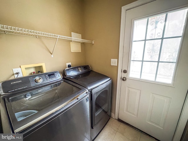 washroom with washing machine and clothes dryer, a wealth of natural light, and light tile patterned floors