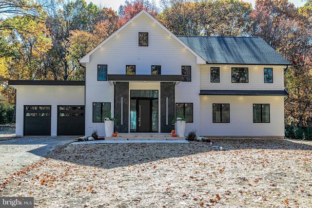 view of front of property with gravel driveway, an attached garage, and a shingled roof