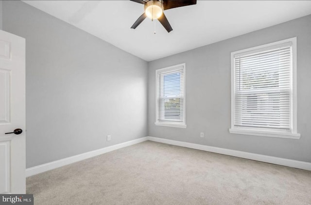 spare room featuring light carpet, vaulted ceiling, and ceiling fan