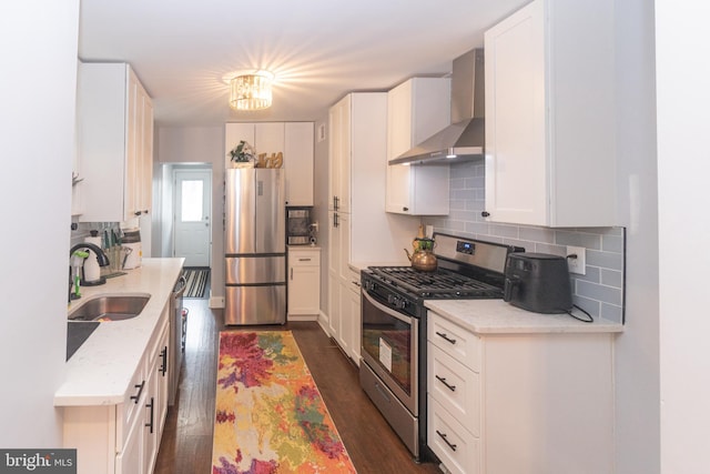 kitchen with white cabinetry, wall chimney range hood, sink, and appliances with stainless steel finishes