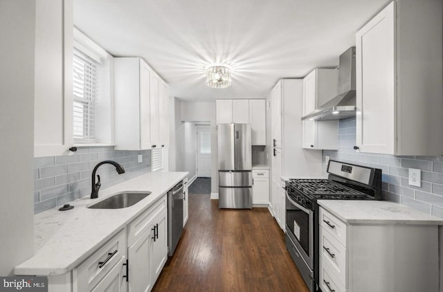 kitchen with light stone counters, white cabinets, stainless steel appliances, and wall chimney exhaust hood