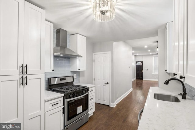 kitchen with white cabinets, stainless steel gas range, sink, and wall chimney range hood