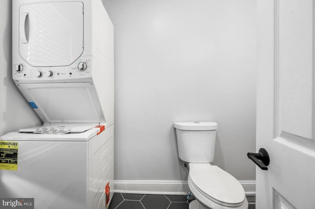 bathroom with tile patterned floors, stacked washer / dryer, and toilet