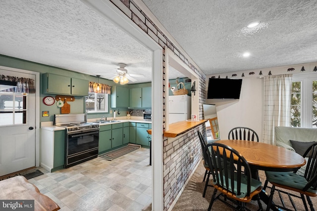 kitchen featuring white fridge, plenty of natural light, green cabinets, and electric range