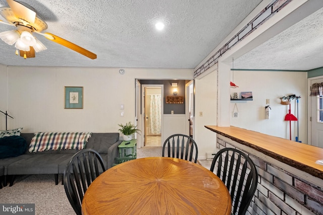 dining room featuring ceiling fan, carpet floors, and a textured ceiling