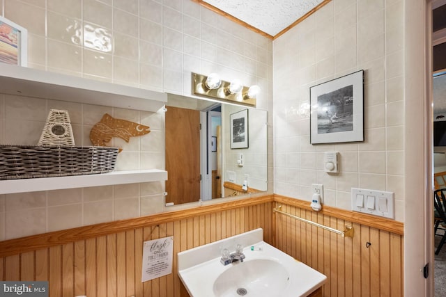 bathroom with crown molding, vanity, tile walls, and a textured ceiling