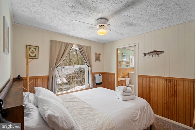 bedroom featuring heating unit, ceiling fan, wooden walls, and a textured ceiling