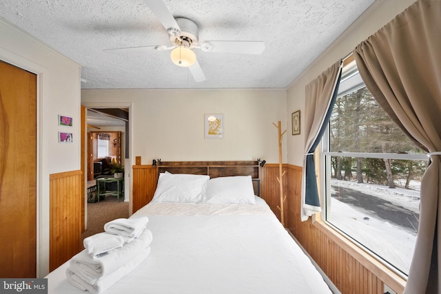 bedroom with ceiling fan, carpet, a textured ceiling, and wood walls