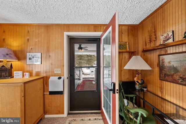 doorway featuring ceiling fan, wooden walls, and a textured ceiling