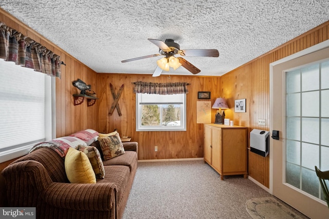 sitting room with light carpet, a textured ceiling, and wood walls